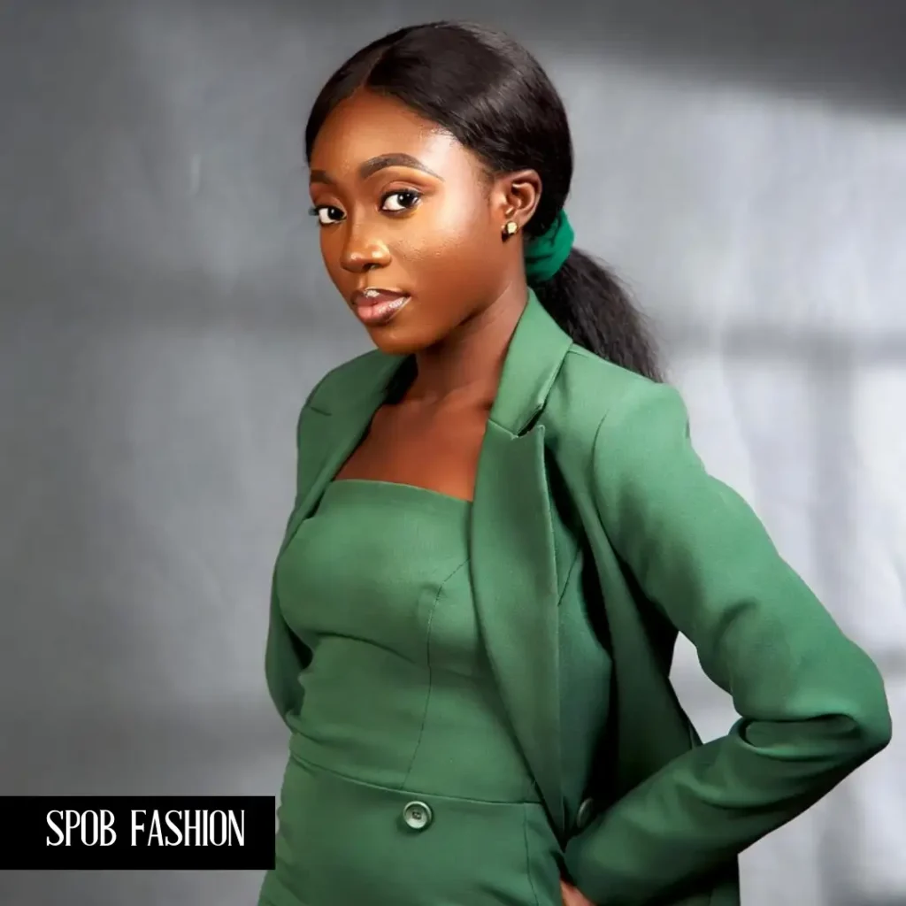 A Black woman wearing a monochromatic forest-green set: a tailored pencil skirt and a matching structured blazer. She has her hair in a sleek low ponytail and is wearing gold stud earrings. Studio-quality professional photography.